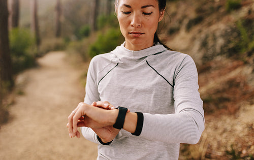Young fitness woman runner checking time on smart watch.