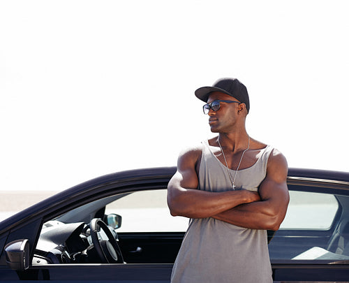 Muscular african man standing by his car