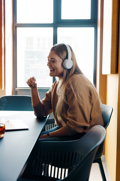 Smiling young woman with headphones enjoying a remote conversation