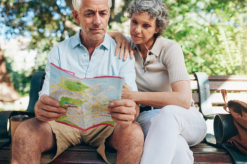 Senior tourist sitting on a park bench with a city map