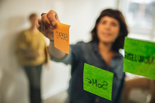 Woman brainstorming using adhesive notes in meeting.