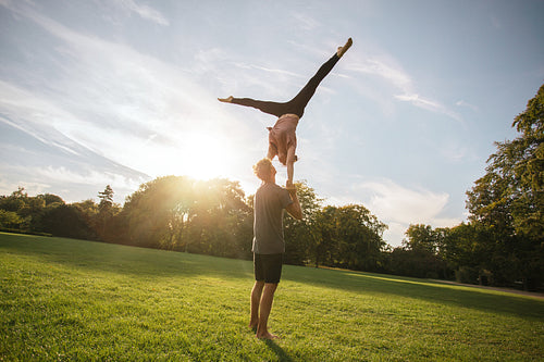 Fit young couple doing acro yoga in park