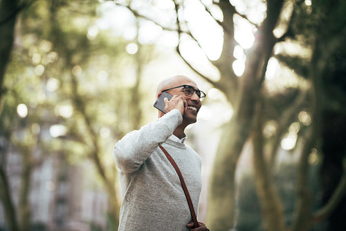 Businessman walking on street to office while talking on cell phone