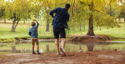 Father and son throwing rocks in pond 