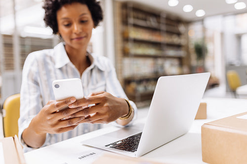 Young online store manager reading a text message on her smartphone