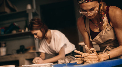 Two women at a pottery workshop making clay pots
