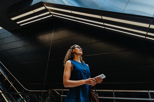 Young woman holds smartphone in modern transit station during commute