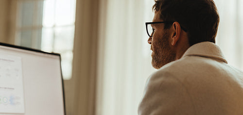 Man works on computer at desk in office with focused attention