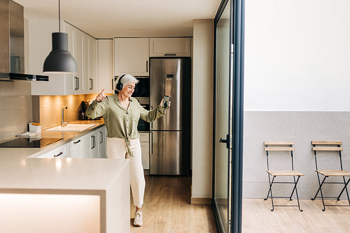 Carefree senior woman dancing to her favourite music at home