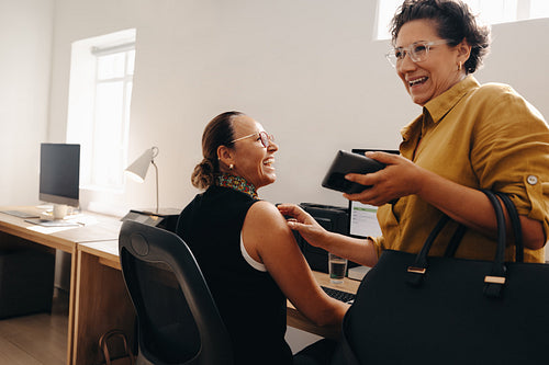 Friendly coworkers sharing a moment of laughter in a modern office setting