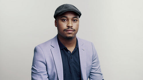 Man in jacket and cap staring at camera