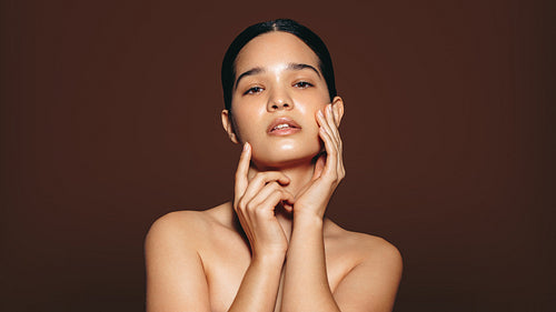 Woman with soft and flawless skin looking at the camera in a studio