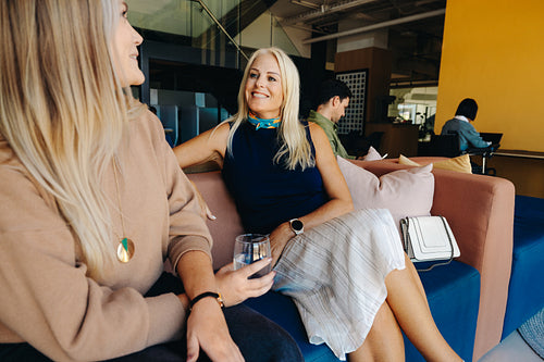 Professional women having a casual discussion at a modern office lounge