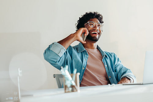 Successful businessman using a smartphone for a phone call conversation in an office