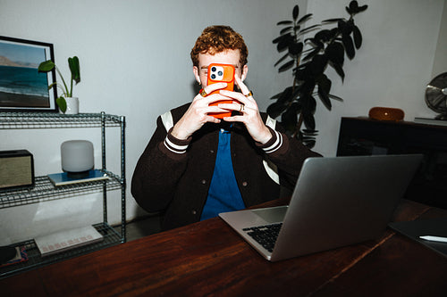 A desk setup for work with a laptop and phone in a casual home office.