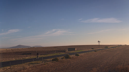 Cyclist riding uphill on long countryside road