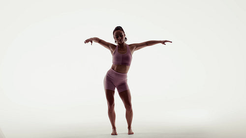 Fit woman exercising with graceful movements and powerful dance in a bright studio