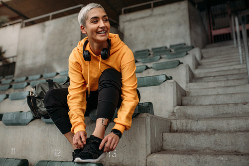 Smiling woman athlete tying shoe lace