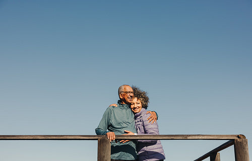 Romantic elderly couple embracing each other on a foot bridge