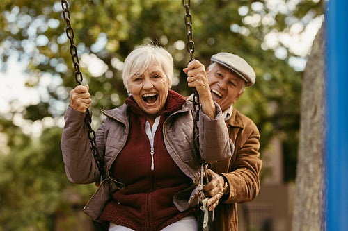 Senior man pushing his partner on swing