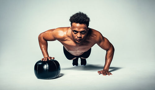 Young fit man doing push up on medicine ball