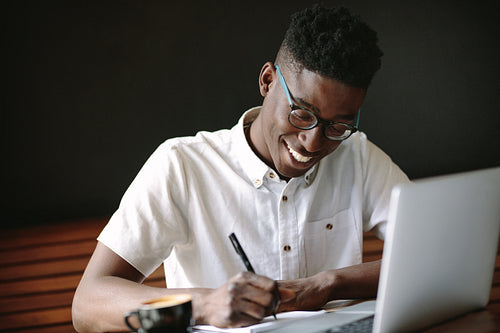 Freelancer sitting with a laptop doing his work at a coffee shop