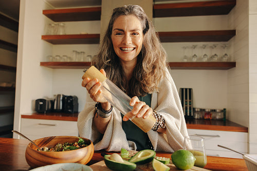 Vegan senior woman preparing a buddha bowl and green juice