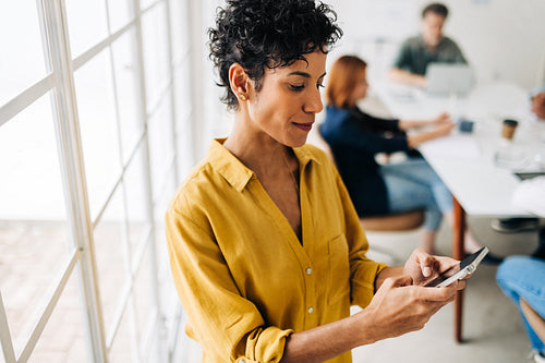 Business woman typing a text message on a mobile phone at work