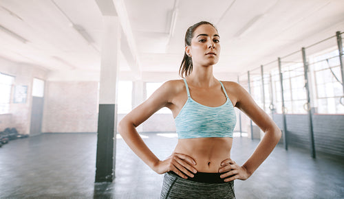 Strong young woman standing in gym