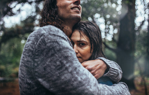 Romantic couple embracing each other in forest in rain