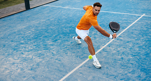 Athlete receives shot on padel court during competitive tournament