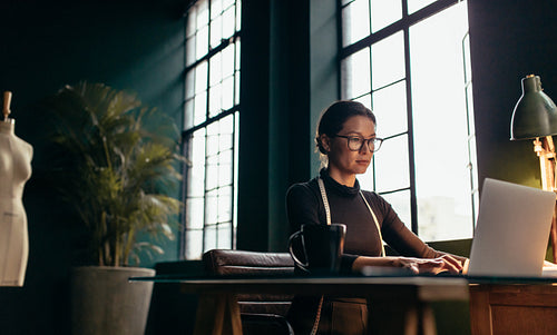 Fashion designer using laptop at her office desk