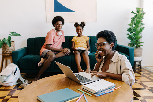 Remote work and parenting: Working mom speaking on the phone at home