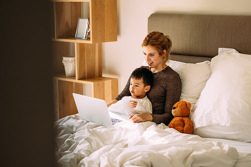 Mother and son watching cartoons on laptop in bed