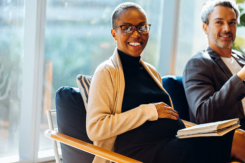 Pregnant woman in casual meeting setting with colleagues smiling during discussion