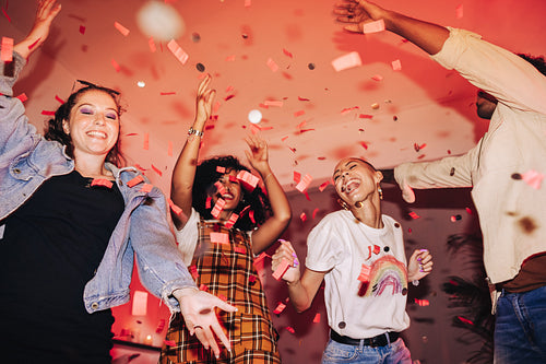 Happy friends dancing under falling confetti