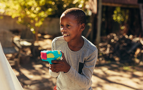 Kid playing with water gun in the backyard