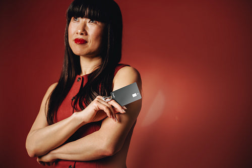 Bank card in focus, the woman stands in a confident studio finance portrait