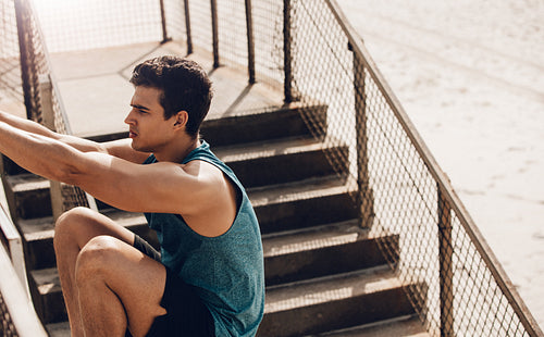 Fitness male stretching outdoors at the beach