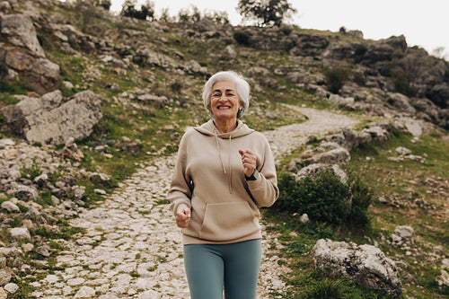 Cheerful senior woman jogging outdoors