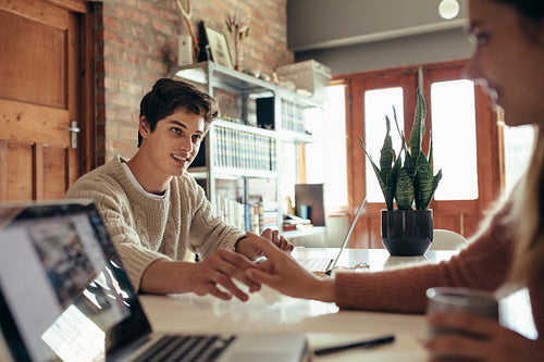 Loving couple sitting at table at home and working
