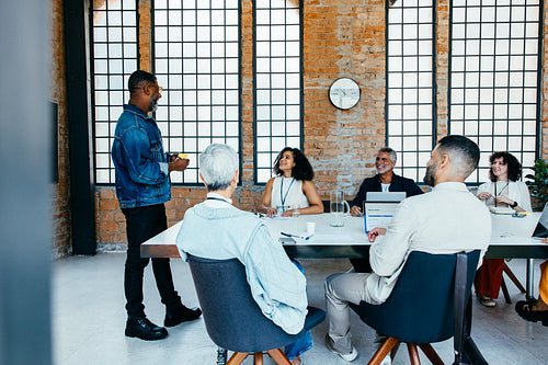 Diverse team engaged in a collaborative meeting around a boardroom table in a modern office setting
