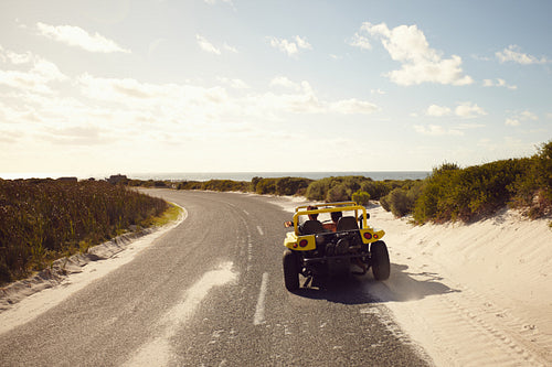Young couple driving down a open road to the beach