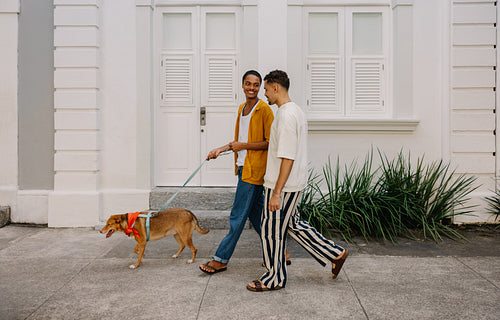 Happy couple walking their dog in a charming urban neighborhood
