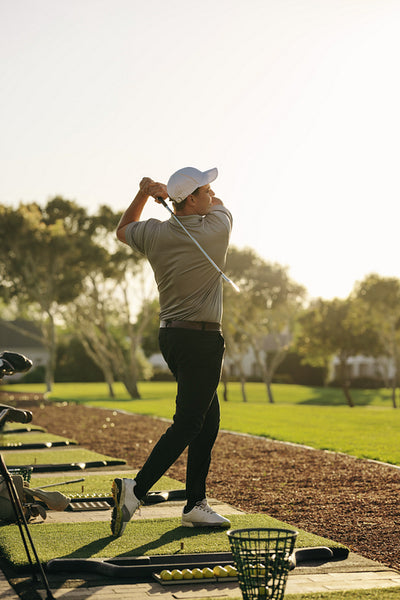 A golf professional honing their technique on the driving range at sunrise.