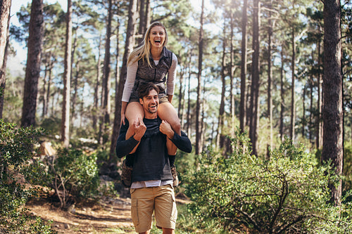 Man carrying his woman partner on his shoulders while trekking in forest