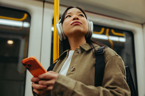 Commuter wearing headphones with smartphone on metro