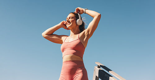 Caucasian sports woman listening to music on headphones outdoors