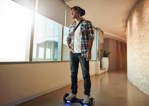 Young man on a hover board in office corridor
