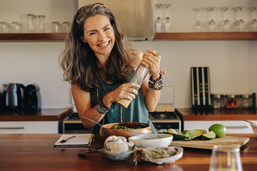 Cheerful senior woman following a healthy vegan recipe at home